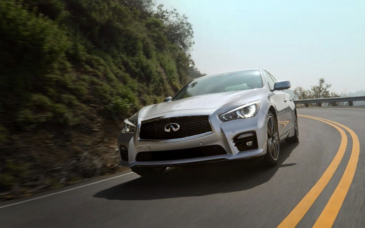 Front view of an INFINITI driving along a curvy highway
