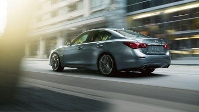 Rear Sideview Of INFINITI Q50 Driving On Street