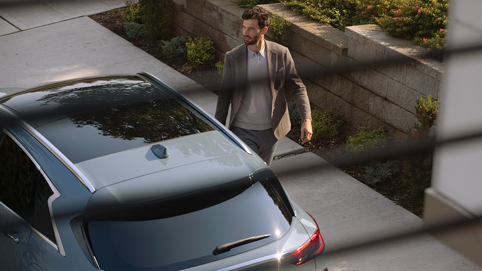 Exterioroverhead view of man walking on the passenger side of an INFINITI QX50