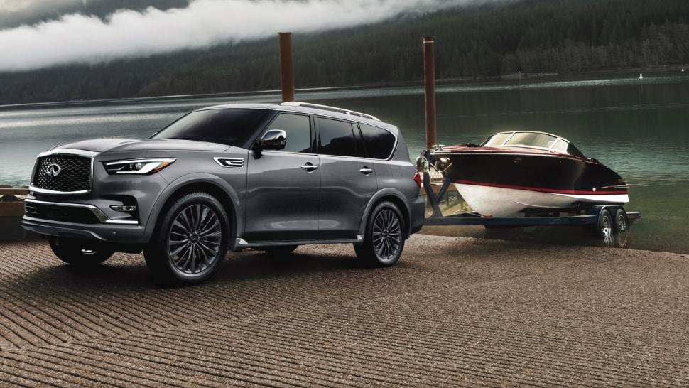 Side profile of 2024 INFINITI QX80 towing a boat highlighting 8500 lb. towing capacity