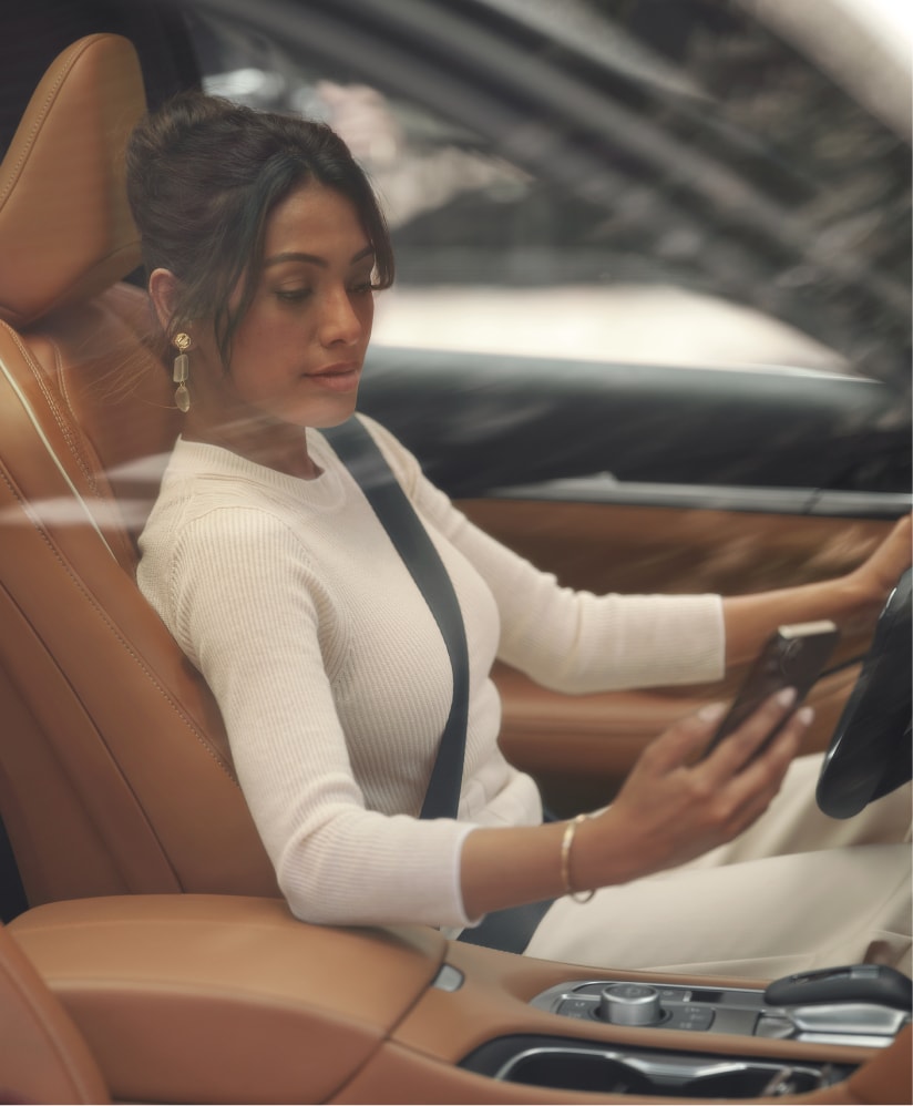 Woman sitting inside of an INFINITI QX60 looking at her phone