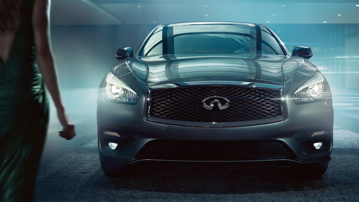 Exterior Front Profile View Of Woman Walking Towards The 2019 INFINITI Q70 Headlights And Front Bumper